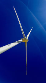 Low angle view of wind turbine against blue sky