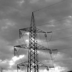 Low angle view of electricity pylon against cloudy sky