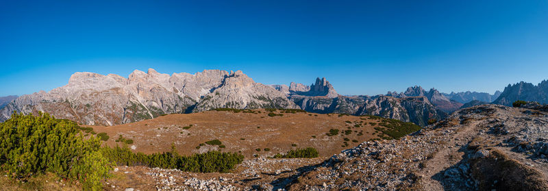 Panoramic view of rocky mountains against blue sky