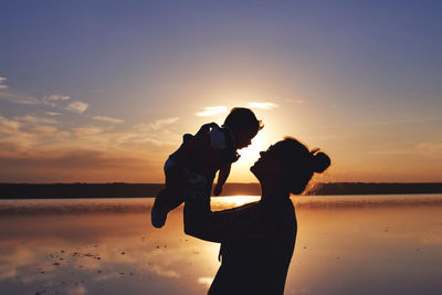 Woman with a child silhouette at the sunset time by the sea