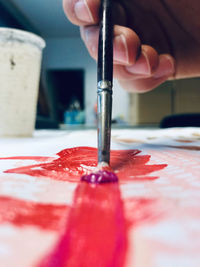 Close-up of hand painting over paper on table