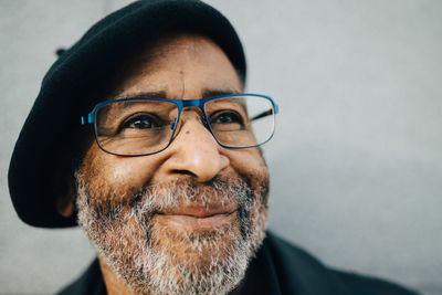 Senior man with eyeglasses looking away against wall