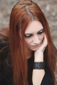 High angle view of thoughtful young woman with hand on chin sitting outdoors