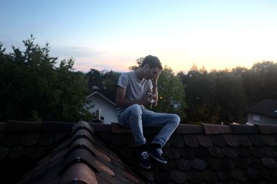 Man smoking cigarette while sitting on rooftop