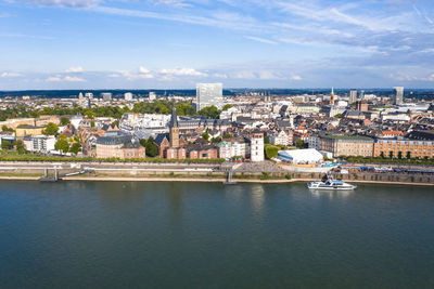 Aerial view of river amidst buildings in city against sky