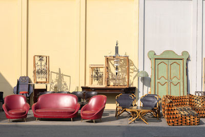 Antique wooden stuffed -furniture, cabinets, sofas, chairs and mirrors leaning outside on the street