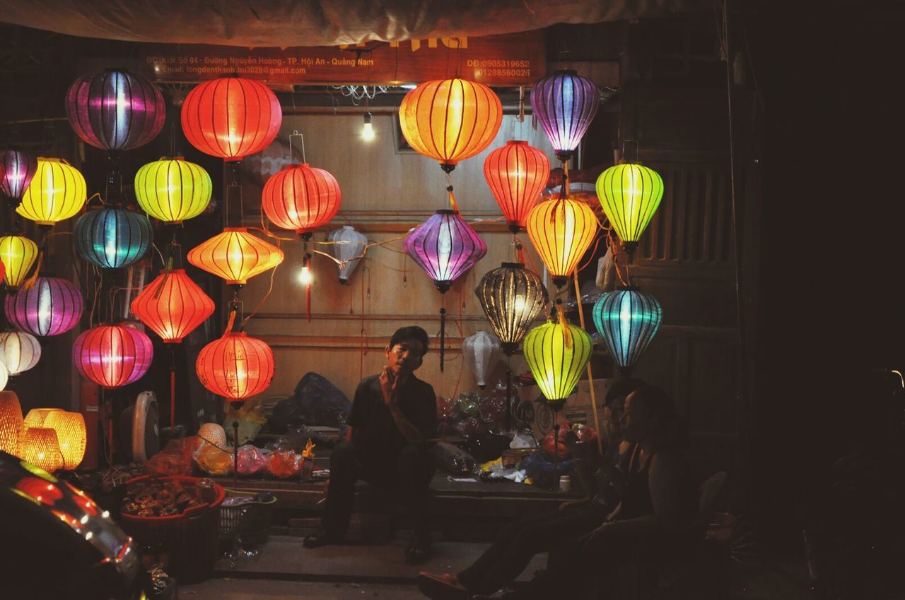 illuminated, indoors, night, celebration, men, lighting equipment, multi colored, lifestyles, person, decoration, leisure activity, lantern, cultures, hanging, retail, large group of people, variation, choice, traditional festival