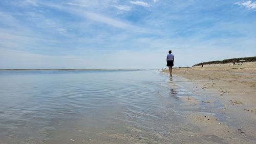 Rear view of man on beach against sky