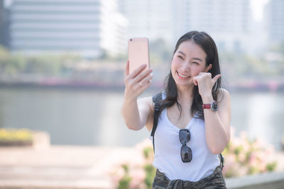 Portrait of woman photographing with mobile phone