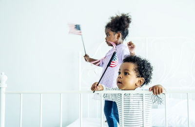 Cute kids holding american flag playing at home