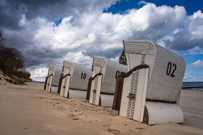 Hooded beach chairs on sand against sky