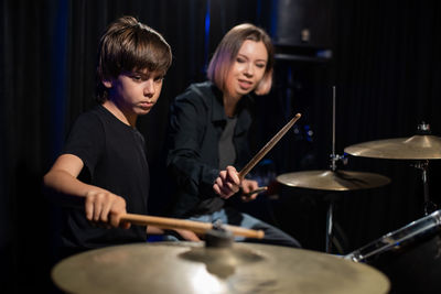 Portrait of young woman playing drum at home