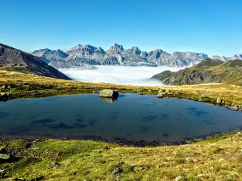 Scenic view of lake and mountains against clear blue sky