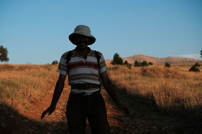 Side view of man standing on field against clear sky