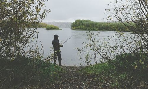 Rear view of man fishing on lake