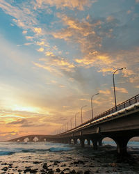 Bridge over sea against sky during sunset
