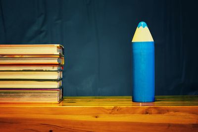 Close-up of artificial pencil by books on wooden table