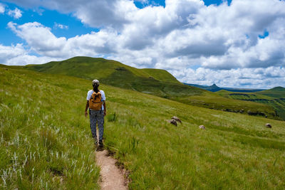 Rear view of woman walking on trail against sky