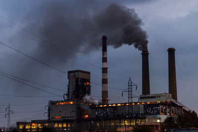 View of coal power plant high pipes with black smoke moving up polluting atmosphere