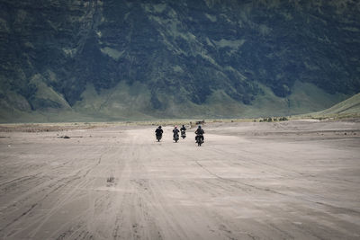 Rear view of people riding motorcycles on mountain road