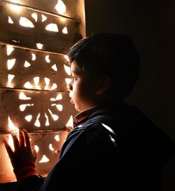 Portrait of boy looking away against illuminated wall