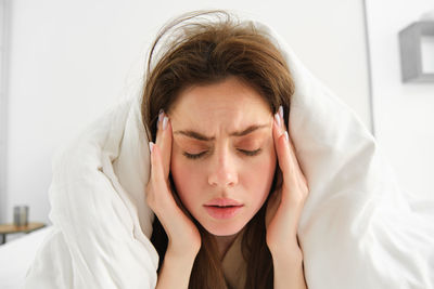 Close-up of young woman lying on bed at home