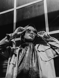 Young woman wearing sunglasses standing against wall