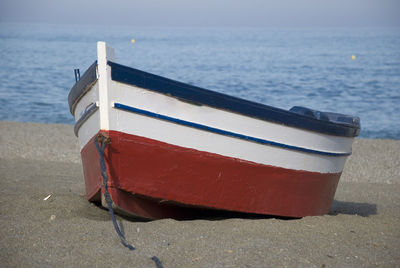 Empty multi colored small wooden rowing boat on beach