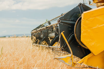 Close-up view of yellow tractor plowing field and collecting ears