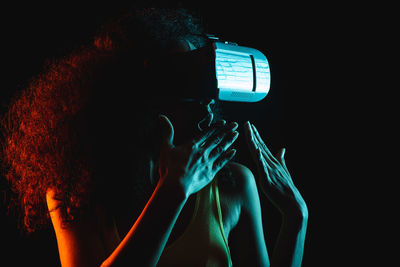 Portrait of woman photographing illuminated light on black background