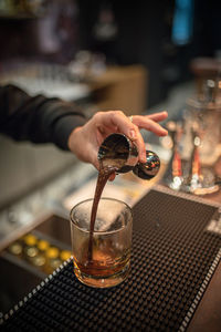 Midsection of person pouring drink in glass