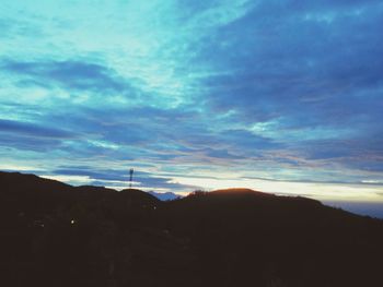 Low angle view of silhouette communications tower against sky during sunset