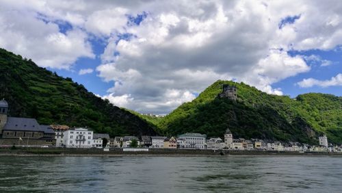 Scenic view of river by buildings against sky