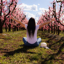 Rear view of woman sitting on grassy field