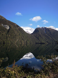 Scenic view of lake and mountains against blue sky