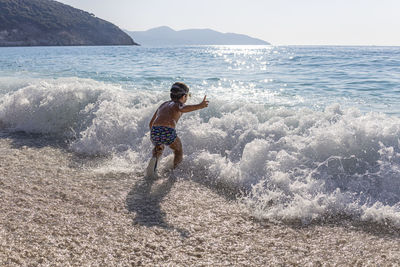 Little kid enjoying the waves on myrtos beach, greece.