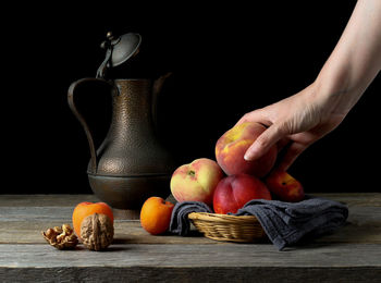 Man holding fruit on table against black background