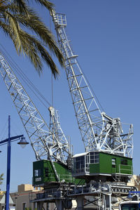 Low angle view of crane against clear blue sky