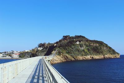 Scenic view of sea and mountains against clear blue sky