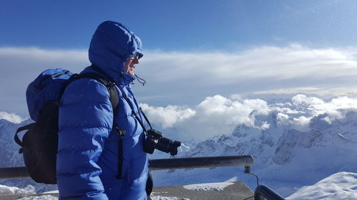 Man standing on snow covered mountain against sky