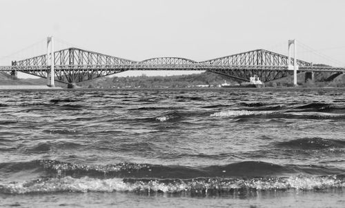 Suspension bridge over sea against clear sky