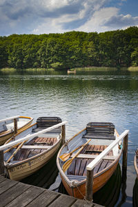 Boats moored by lake against sky