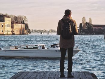 Rear view of man standing by sea against sky