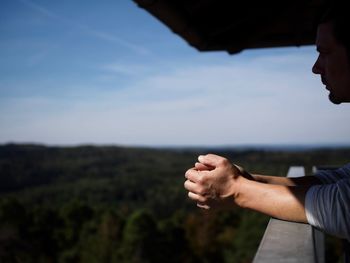 Man leaning on railing of balcony