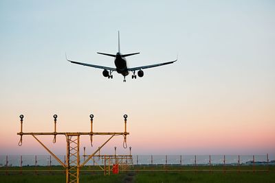 Airplane landing at airport runway during sunset