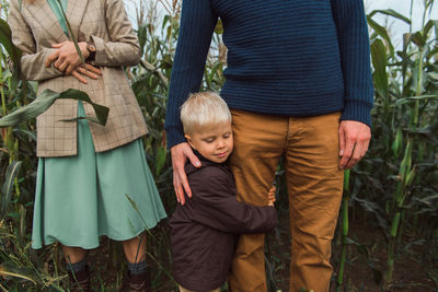 Family walking in corn field at autumn, kid hug parent