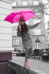 Woman holding umbrella on street in rain