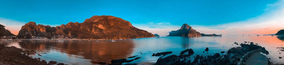 Panoramic view of sea and rocks against blue sky