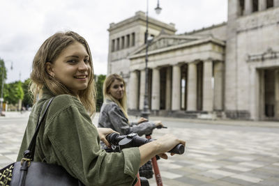 Portrait of smiling woman sitting on city street