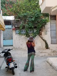 Rear view of woman wearing hat against building